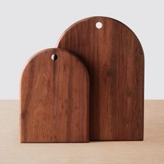 two wooden cutting boards sitting on top of a table next to each other with holes in them