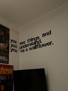 a television sitting on top of a wooden table next to a wall with movie posters