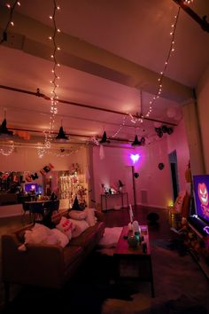 a living room filled with lots of furniture and lights hanging from the ceiling above it