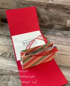 the inside of a red and white gift bag on top of a wooden table next to a greeting card