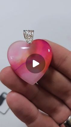 a person holding a pink heart shaped object with a diamond in it's center