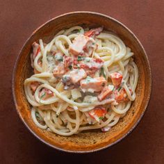 a brown bowl filled with pasta and meat