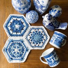 blue and white crocheted items are arranged on a wooden table with coffee mugs