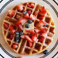 a waffle topped with strawberries and blueberries on top of a white plate