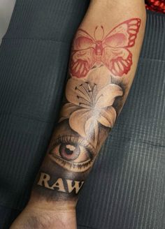 a person with a butterfly and eye tattoo on their arm that says raw, in front of them is a flower