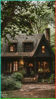 a black house with lots of windows and plants on the front porch is surrounded by greenery