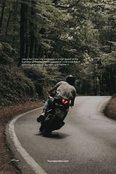 a man riding a motorcycle down a curvy road in the middle of trees