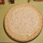 an uncooked pie sitting on top of a counter next to other food items