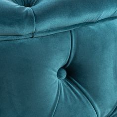 a close up view of the back of a blue velvet couch with buttons on it