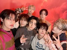 the group of young men are posing together for a photo in front of a red background