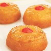 three pineapple cakes on a white plate with red cherries in the top and bottom