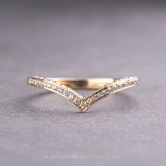 a gold ring with two rows of diamonds on the top and bottom, sitting on a gray surface