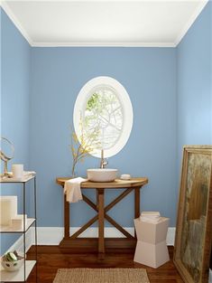 a bathroom with blue walls and white trim on the walls, wood flooring and a round window