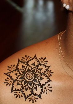 a woman with a tattoo on her shoulder that has a circular design in the middle