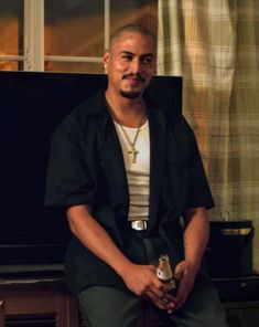 a man sitting in front of a tv holding a drink and looking at the camera