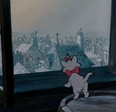 the cat is looking out the window at the city from it's rooftops