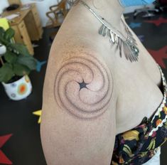 a woman with a tattoo on her shoulder has a spiral design on her left arm