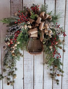 a christmas wreath hanging on the side of a white wooden wall with pine cones and berries