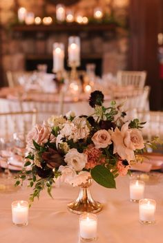 a centerpiece with flowers and candles on a table