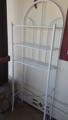 a white metal shelf sitting next to a wall