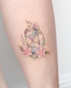 a tattoo with an hourglass and flowers on the side of someone's leg