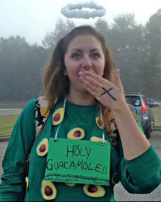 a woman wearing an ugly guacamole sign on her shirt and eating something