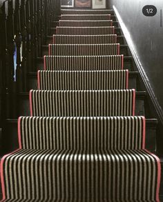 the stairs are lined with black and white striped carpet, along with pictures on the wall