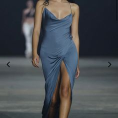 a woman walking down a runway wearing a blue dress with slits on the sides