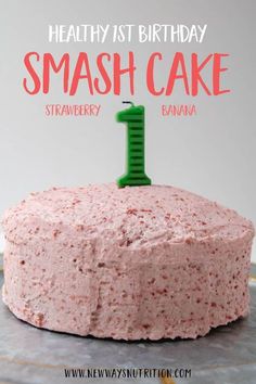 a cake with pink frosting and a green candle on top that says, healthy 1st birthday smash cake strawberry banana