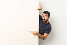 a man is peeking out from behind a white wall and pointing his finger at the corner