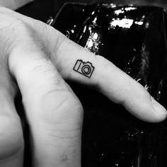 a person with a camera tattoo on their finger