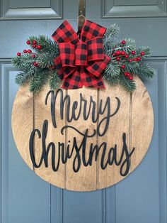 a wooden sign that says merry christmas hanging on a door with evergreen and red berries