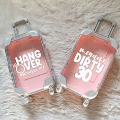 two pieces of pink luggage sitting on top of a white rug with the words hang over dirty