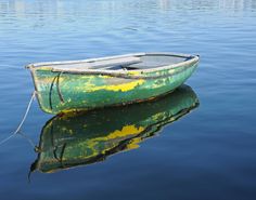 a small green boat floating on top of a lake