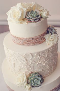 a three tiered wedding cake with succulents and lace