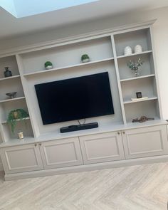 a flat screen tv sitting on top of a white entertainment center with built in shelves