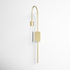 a white wall with a gold handle on it and a glass tube hanging from the side