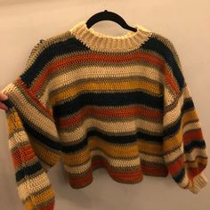 a multicolored sweater hanging on a hanger in front of a white wall