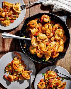 two plates with shrimp and vegetables on them next to silverware, forks and napkins