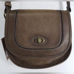 Justin Dark Brown Leather Saddle Bag Crossbody - Purse. Fold Over Top Flap With Metal Turn Button. Interior Has 1 Large Zip Pocket And 2 Medium Slip Pockets. Burnished Brass Colored Hardware. Measures 8.5" T X 9" W At The Bottom - 2.5" - 3.25" D. Has 53" Adjustable Strap. Brand New-Original Tags Retro Everyday Saddle Satchel Bag, Brown Saddle Shoulder Bag With Turn-lock Closure, Retro Saddle Bag For Daily Use, Classic Shoulder Bag With Snap Closure For Errands, Vintage Satchel With Metal Hardware, Vintage Shoulder Bag With Metal Hardware, Retro Leather Saddle Bag, Vintage Shoulder Bag With Metal Hardware For Everyday, Everyday Vintage Shoulder Bag With Metal Hardware