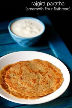 two flatbreads on a white plate next to a bowl of yogurt