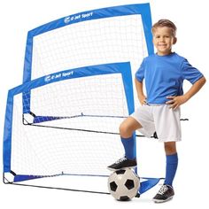 a young boy standing next to a soccer goal with a ball in front of it