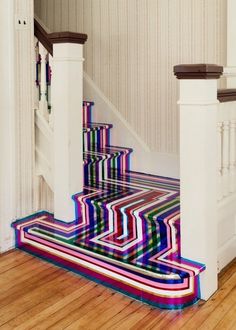 a stair case painted with multicolored stripes on the bottom and bottom, next to a banister