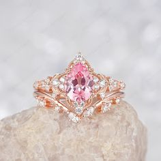 a pink diamond ring sitting on top of a rock with white diamonds around the band