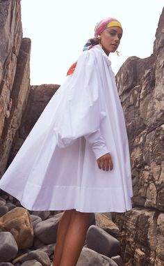 Our whimsical signature poplin shirt dress, crafted from soft Italian cotton, showcases pleating along the shoulders and back, creating a beautifully flowing silhouette. It features exaggerated bustled sleeves, worn multiple ways, crisp inverted buttoned cuffs, and inseam side pockets. Detailed with covered buttons and a versatile asymmetrical neckline, it strikes the perfect balance between masculine structure and feminine elegance, offering effortless sophistication, day or night. A must-have Poplin Shirt Dress, Feminine Elegance, Puff Sleeve Shirt, Asymmetrical Neckline, Dress Shirt Sleeves, British Indian, Poplin Shirt, Brunei, Covered Buttons