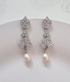 a pair of white pearls and crystal earrings on a plate with a floral design in the background