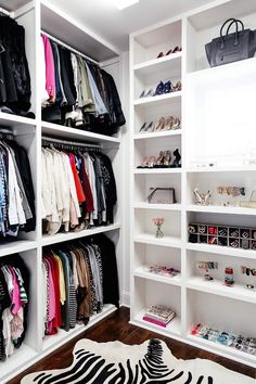 an organized closet with white shelves and zebra rug