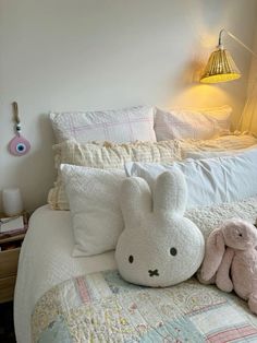 two stuffed animals sitting on top of a bed next to pillows and blankets in a bedroom