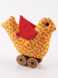 a yellow and red bird sitting on top of wooden wheels