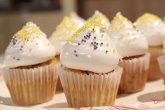 cupcakes with white frosting and gold sprinkles on a plate